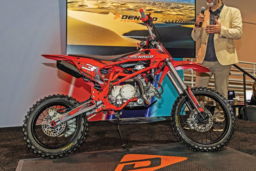Red mini dirt bike on a stage at a convention.